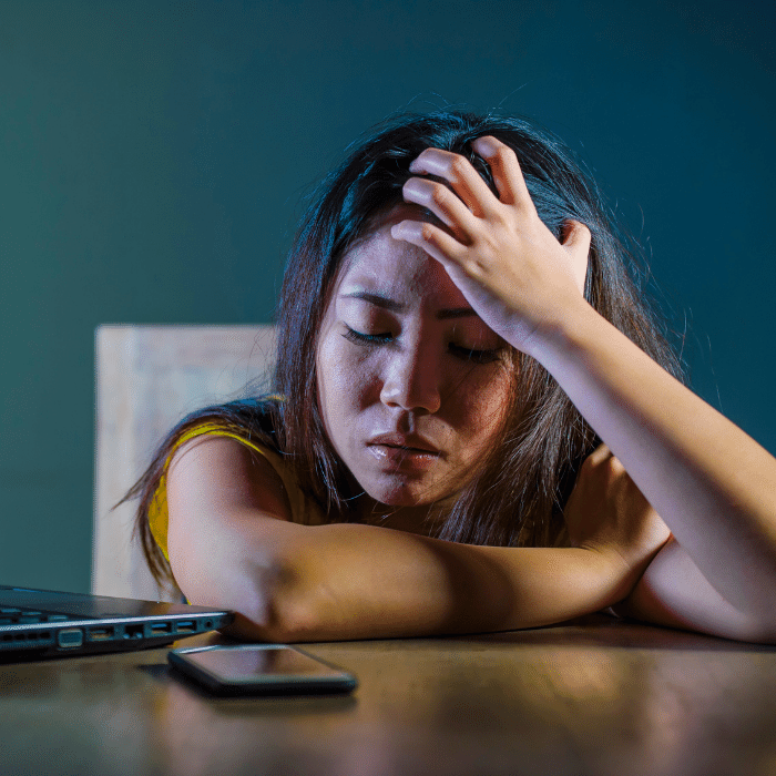 woman with head in hand looking at her phone